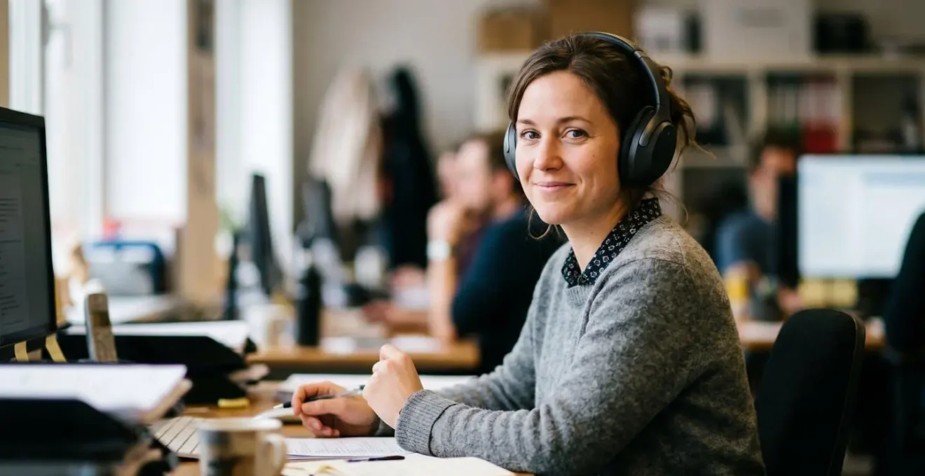 Un employé en open space utilise son casque sur une seule oreille pour signaler sa disponibilité.